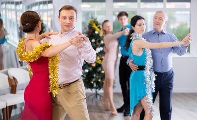 Smiling man dancing elegant slow ballroom dance with female partner in stylish dress decorated with...