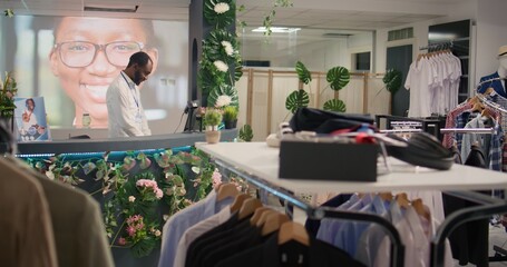 Fototapeta na wymiar BIPOC man working in luxurious clothing store with elegant assortment of blazers. African american shopkeeper awaiting clients in premium fashion boutique with stylish attire garments