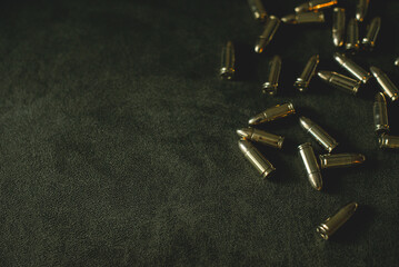 bullets for a combat pistol 9 mm gold color lies on a dark green or khaki background top view...