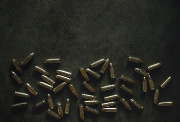 bullets for a combat pistol 9 mm gold color lies on a dark green or khaki background top view close-up