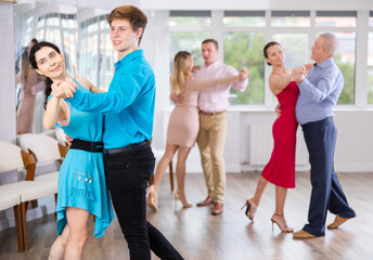 Woman paired with male partner dance samba in class with students