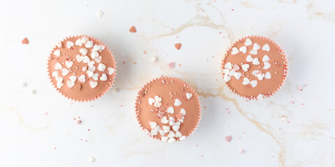 Romantic Valentine's or birthday cupcakes covered glaze in trendy color 2024 Peach Fuzz with heart shape sprinkles.