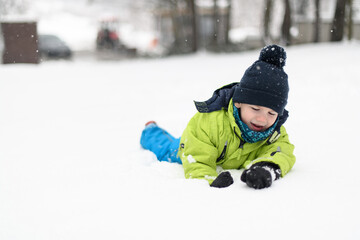 Fototapeta na wymiar Happy Little Kid is Playing in Snow