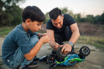 Boy is holding a part of broken toy car while repairing it with his father.