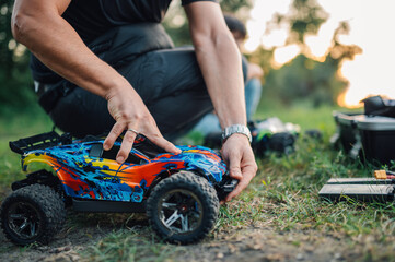 Fototapeta na wymiar Selective focus on toy car reassembled by adult man in nature.