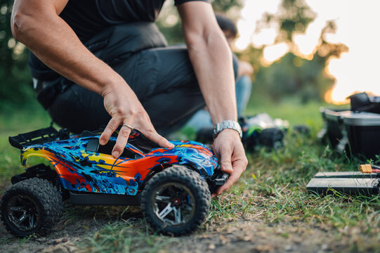 Selective focus on toy car reassembled by adult man in nature.