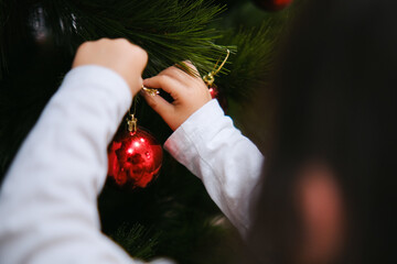 Mano de niña pequeña decorando árbol de Navidad