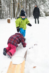 Fototapeta na wymiar Kids Falling Down From Sledge in Winter Park