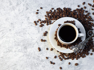 a cup of coffee on a stone white table, roasted coffee beans, top view copy space