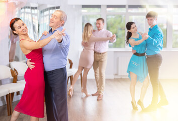 Happy aged man learning to dance Vienneze waltz with female partner in dancing class. Active hobby...