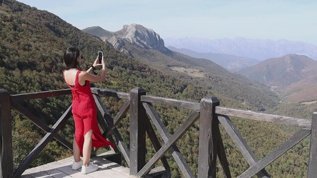 woman in a viewpoint in the mountains takes a picture, excursion and trip concepts
