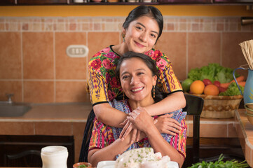 Mother's Day. Mother and daughter in the kitchen smiling at the camera.