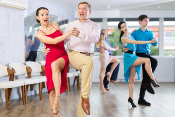 Fototapeta na wymiar Dynamic pair engaging in Latino dance in dance studio. Pairs training ballroom dance in hall