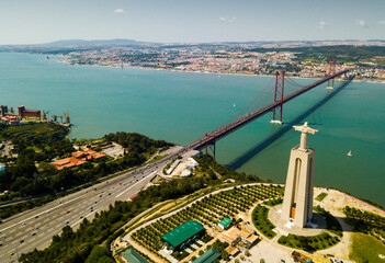 Aerial view over the April of 25 bridge in Lisbon, crossing the Tagus River and Statue of Jesus , Portugal