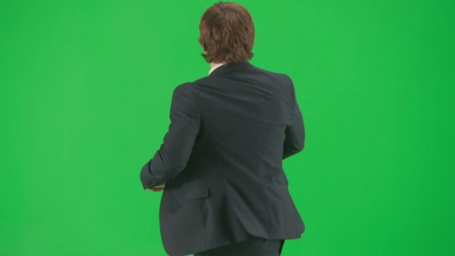 Portrait of male model in suit on chroma key green screen background. Stylish young businessman in trendy suit walking and dancing.