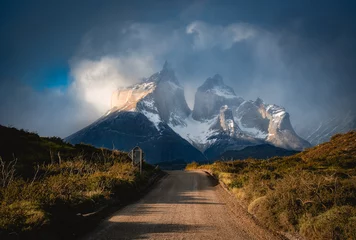 Fototapete Cuernos del Paine a road to the snow mountain under clouds and sun light