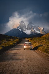 Papier Peint photo autocollant Cuernos del Paine a car on a road to the snow mountain under clouds and sun light