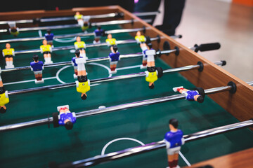 Group of friends playing kicker in a sports bar room, colleagues teammates play table football, table soccer game in the office, having fun, tabletop football match competition at work - Powered by Adobe
