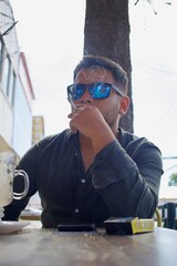 latin man with sunglasses smoking a cigarette