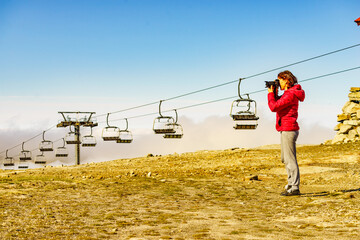 Woman with camera in mountains take travel photo