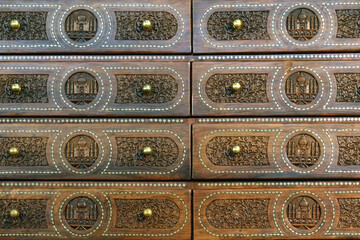 Antique oriental chest of drawers. The drawers are decorated with carvings and a Muslim mosque is depicted in the center.