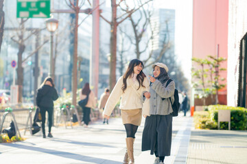 woman girl tourist Two Asian friends but different religions, one of whom is a Muslim girl. Walking tour of the city, city view, traveling in Japan. with fun She is traveling in the city area.