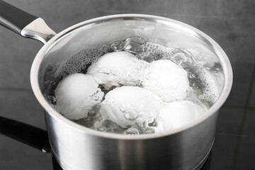 Fototapeta na wymiar Chicken eggs boiling in saucepan on electric stove, closeup