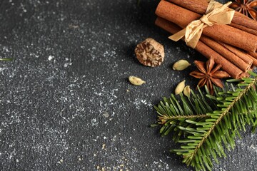 Different aromatic spices and fir branches on grey textured table, flat lay. Space for text