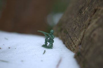 Small green toy solider resting in the snow. 