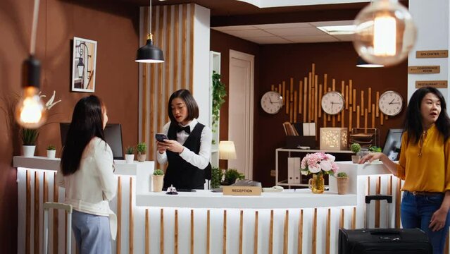 Hotel guest paying with card on pos terminal at check in, ensuring relaxing stay at five star resort on vacation. Asian woman making sure she paid for her accommodation at reception front desk.