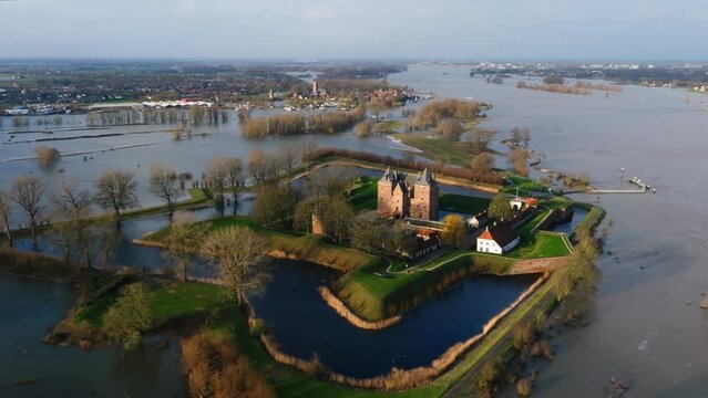 Low aerial orbiting view of the historic Slot Loevestein castle surrounded by flood waters as the Waal River overflows its banks after heavy rains pummel Northern Europe