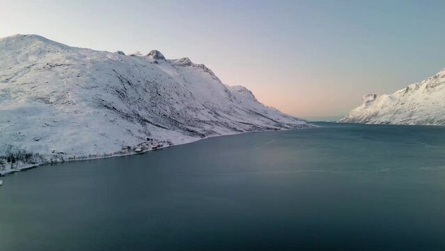 Aerial establishing shot of a frozen lake between mountains in ersfjordvegen