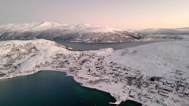Aerial establishing shot of the small village ersfjordvegen surrounded by snow