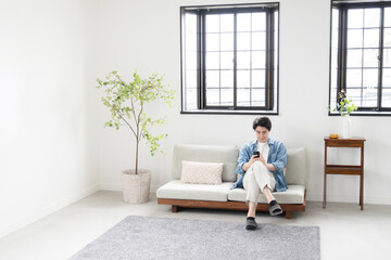 Fototapeta premium Wide angle of middle man on phone in living room Spring and summer image of a bright living room