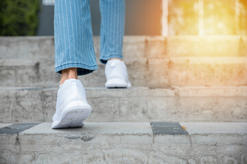 With sneakers on, a woman takes on the city stairway, showcasing her determination and progress....