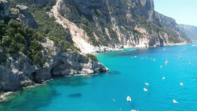 Cala Goloritze shore crowded with boat tourism, Sardinia. Aerial