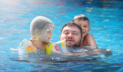 Children hugging dad in the pool