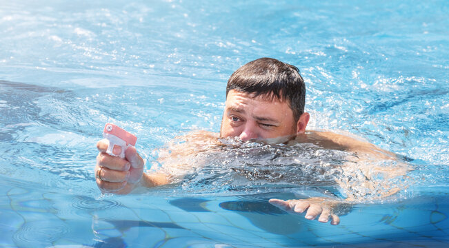 Man playing with water gun in swimming pool