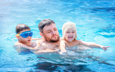 Fototapeta premium Portrait of a father with children in the pool