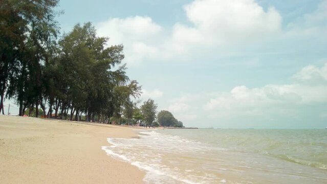 Daytime view of Pantai Puteri Beach in Malacca, Malaysia. Waves from the sea washing ashore and dissolving into the sandy beach.
