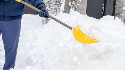 Man shoveling snow off of his driveway after a winter storm in Canada. Man with snow shovel cleans...