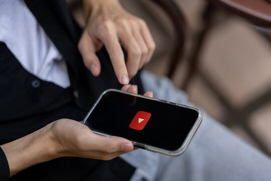 A man using Youtube application on his iPhone while sitting outdoors. close-up image