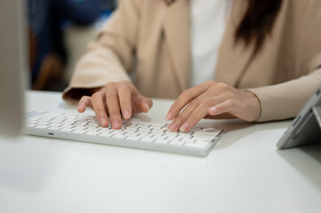 Fototapeta premium Close-up image of a businesswoman working at her desk in the office, typing on keyboard computer.