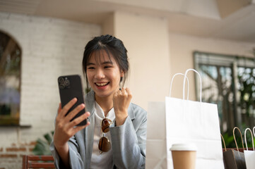 Young cheerful and pretty Asian woman is receiving a good news while sitting in a cafe.