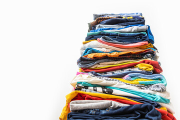 A very tall stack of folded colored clothes for charity, washing, ironing and sorting.