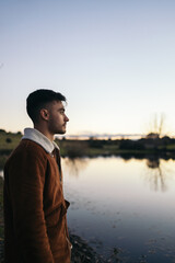 Young man watching the sunset at a lake in the countryside