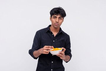 Young man with uncertain expression holding snacks