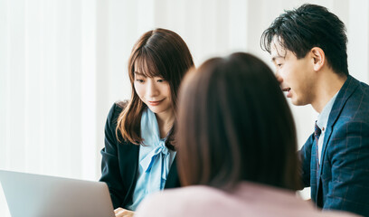 パソコンを見ながらミーティングをする3人のビジネスマン