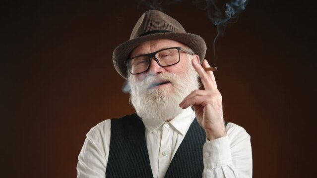 A senior man with a white beard exudes a reflective calm, holding a cigar in a thoughtful pose, his vintage attire and fedora suggesting a story of sophistication and time-honored traditions. 8K RAW.