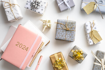 Pink coral colored diary for the year 2024 and New Year's gift boxes, pen, white background